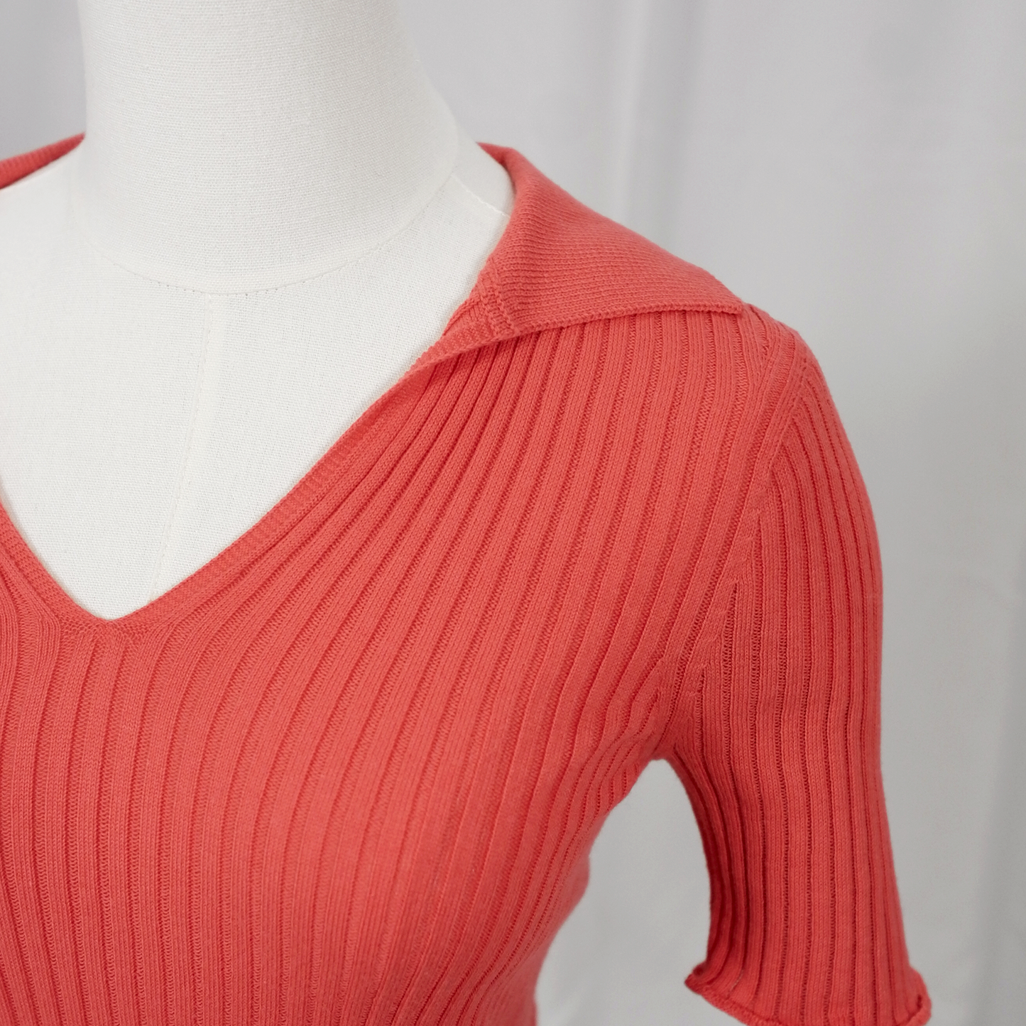 Coral rib knit short sleeve polo on a white background - close up