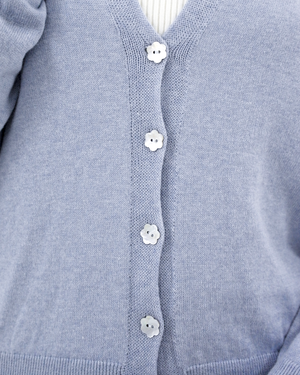 Close-up of the Jasmin cotton cardigan in Cielo blue with flower-shaped mother-of-pearl buttons