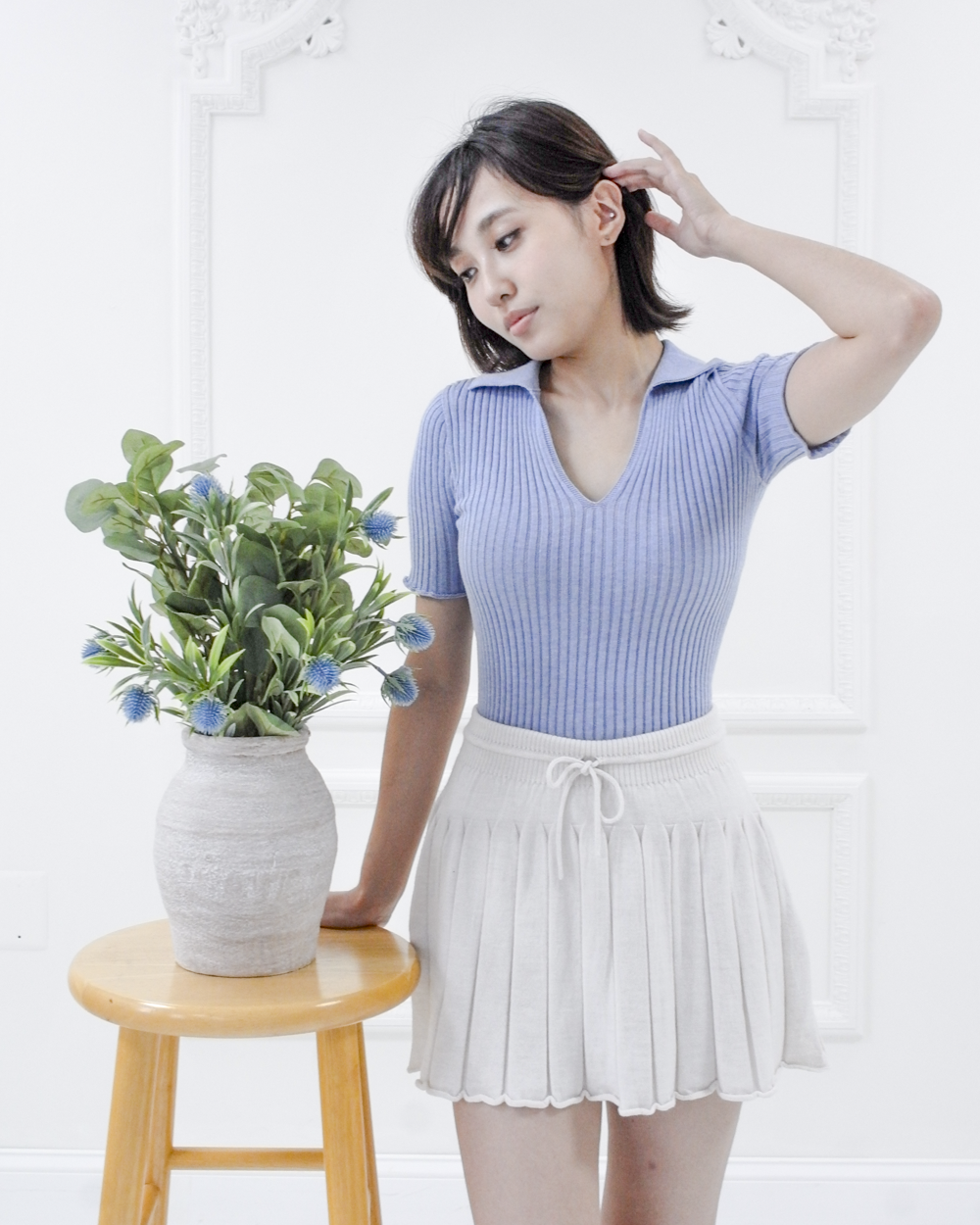 Full-length view of the Corinne cotton knit polo in Cielo blue styled with a white pleated skirt