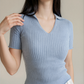 Woman wearing a light blue ribbed knit top against a neutral background
