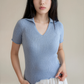 Woman wearing a light blue ribbed knit top against a plain background