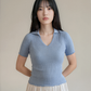 Woman wearing a light blue ribbed sweater against a plain background