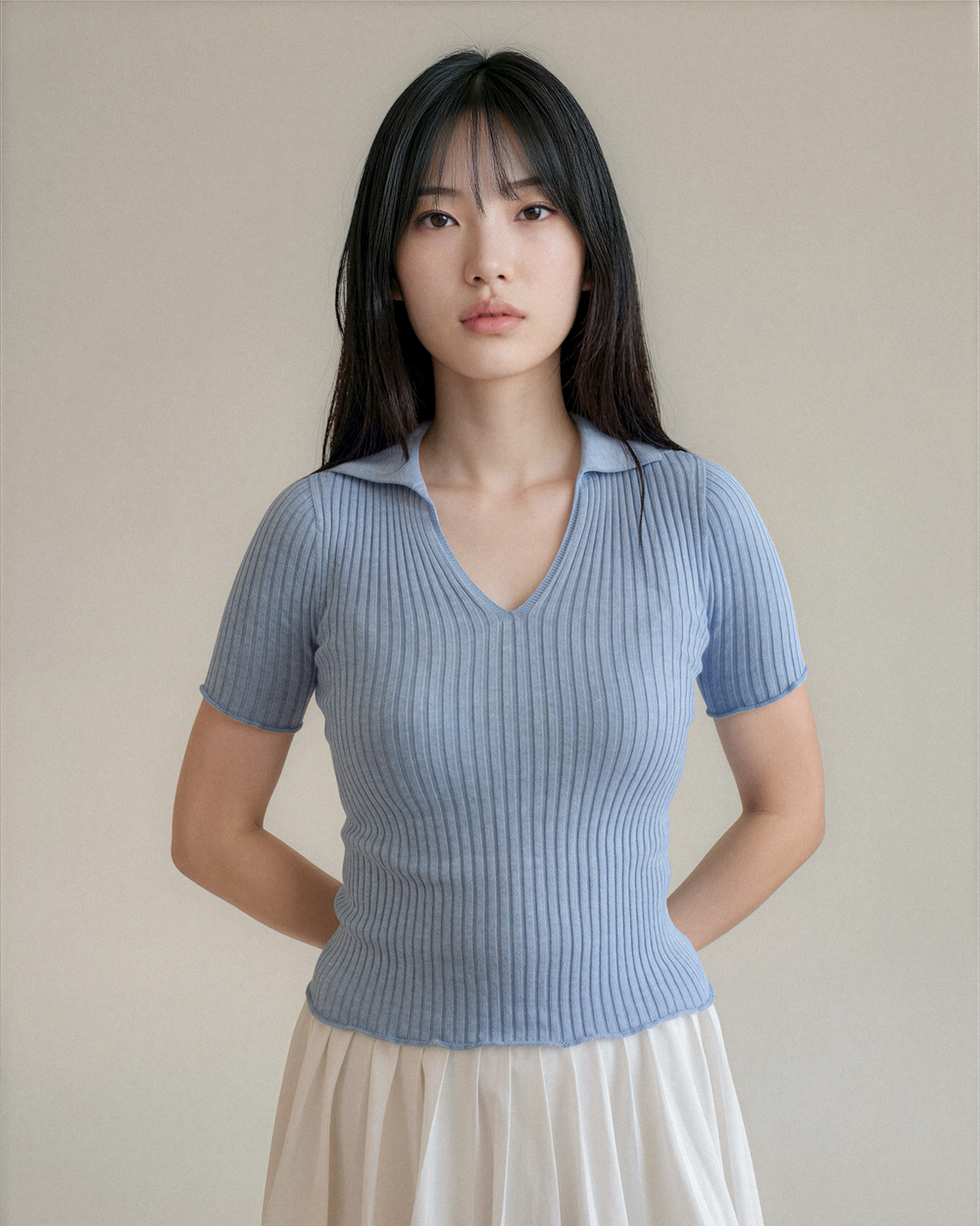 Woman wearing a light blue ribbed sweater against a plain background