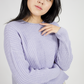Woman wearing a light purple sweater against a plain background