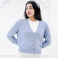 Model wearing the Jasmin cotton cardigan in Cielo blue layered over a white ribbed top, front three-quarter view