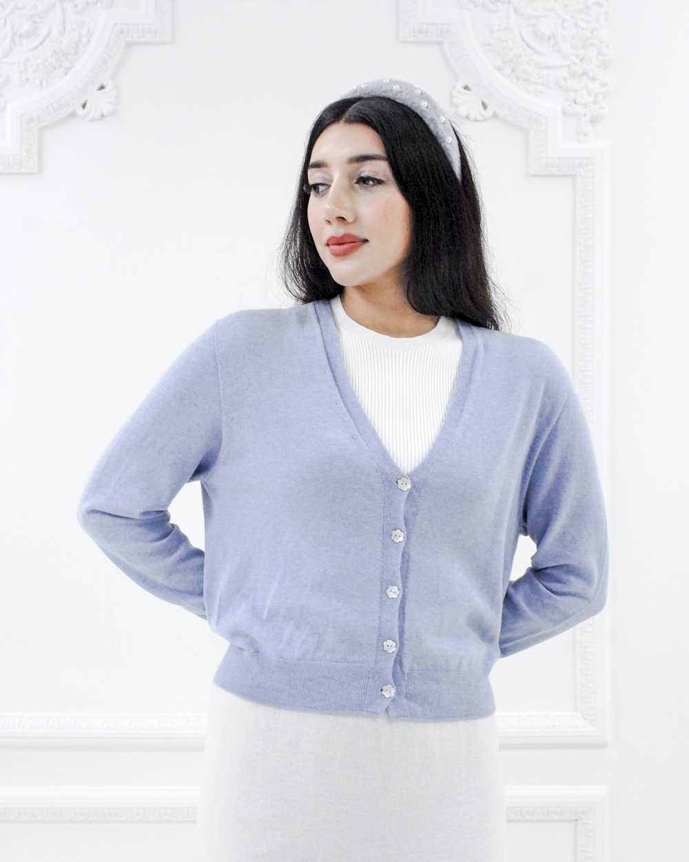 Model wearing the Jasmin cotton cardigan in Cielo blue layered over a white ribbed top, front three-quarter view