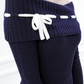 Close-up of the Lisette navy merino off-shoulder top with a white ribbon bow and ribbed foldover neckline