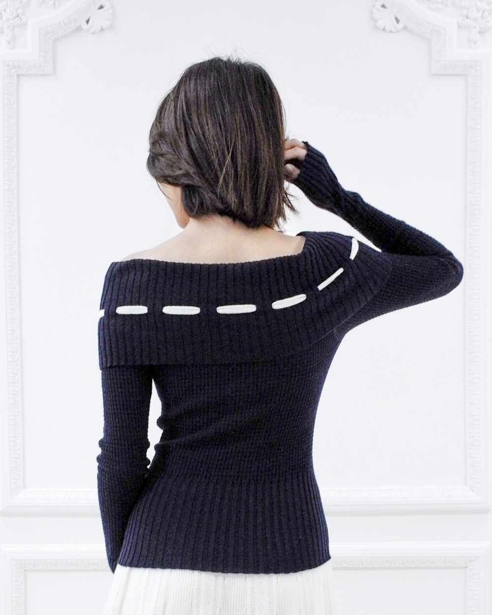 Back view of the Lisette navy merino off-shoulder top showing the ribbed foldover neckline and white ribbon detail