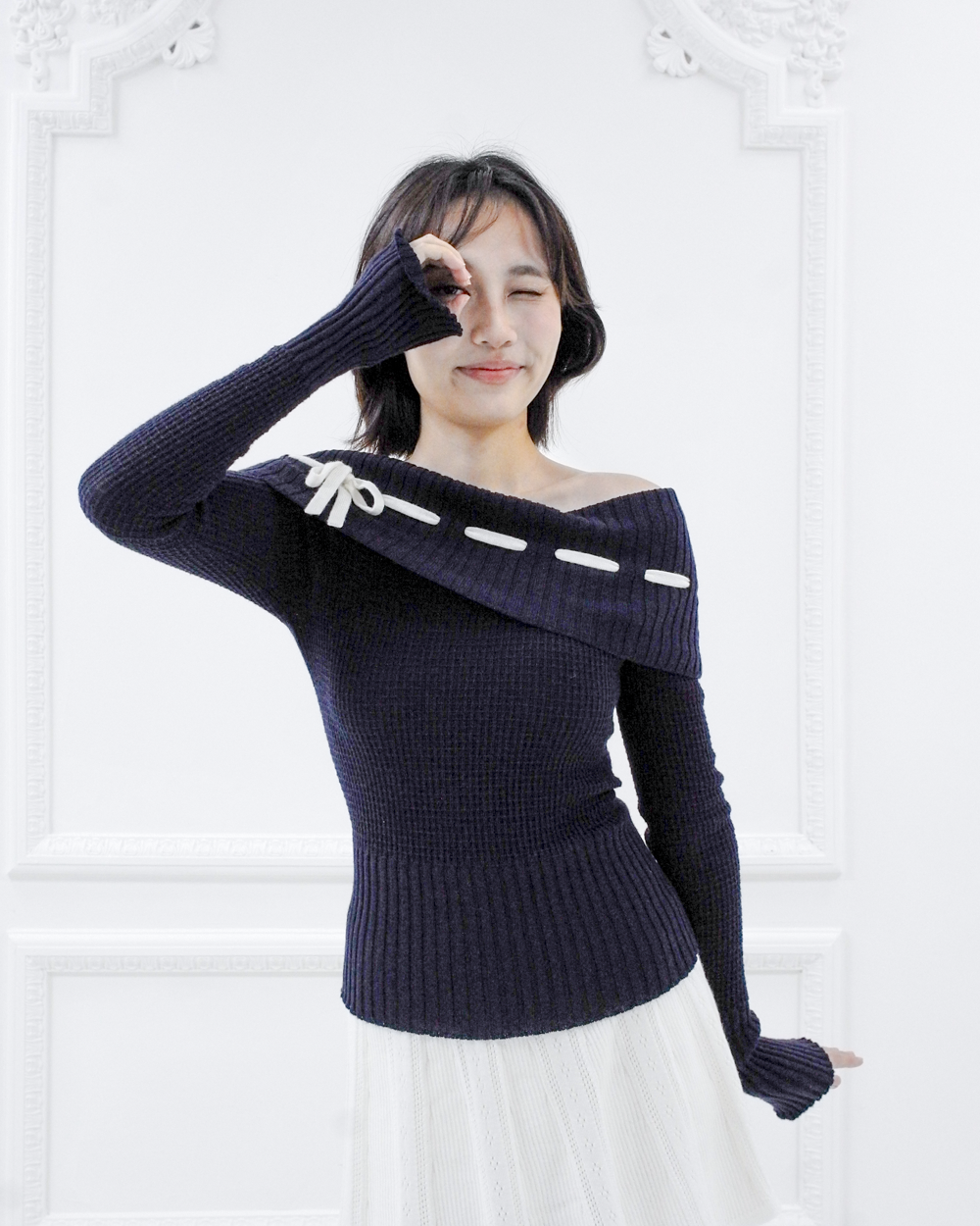 Model wearing the Lisette navy merino off-shoulder top with white ribbon detail and elongated sleeves, front view