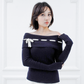 Front view of the Lisette navy merino off-shoulder top styled with a white knit skirt