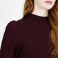 Person wearing a dark maroon sweater against a white background