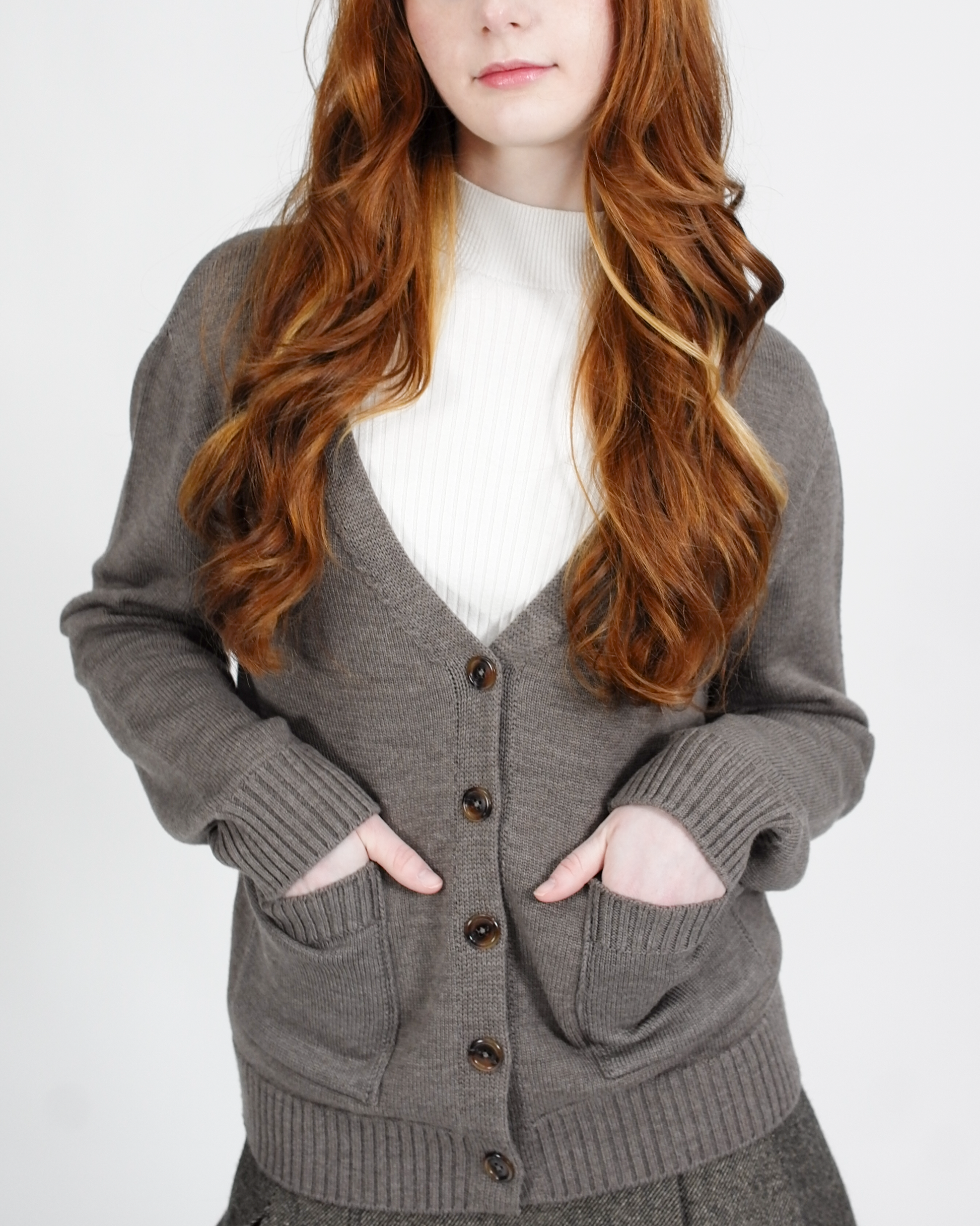 Person wearing a gray cardigan over a white shirt on a plain background