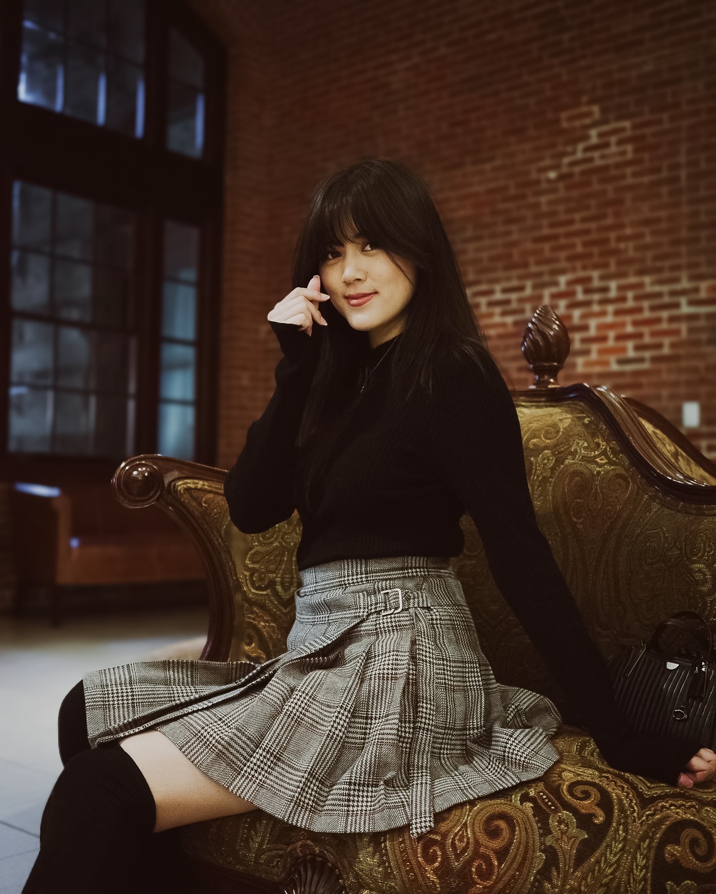 Woman sitting on a decorative chair in a room with brick walls.