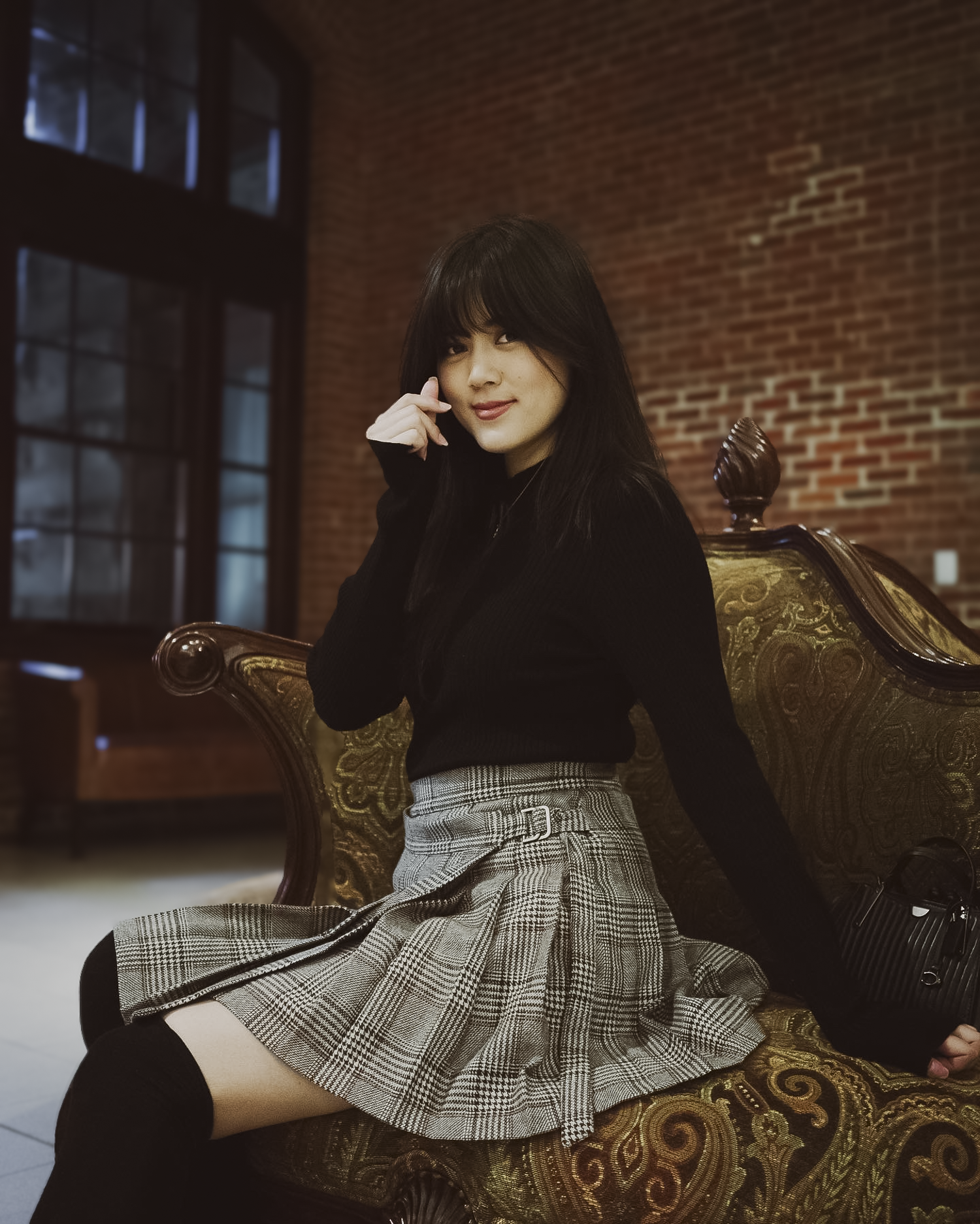 Woman sitting on a decorative chair in a room with brick walls.